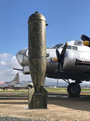 Close-up of a vintage aircraft propeller blade with a silver plane in the background.