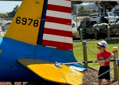 Child exploring colorful airplane tail outdoors.