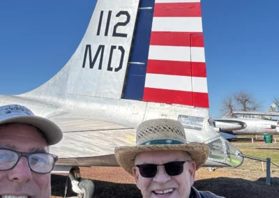 Two men and dog by airplane tail.