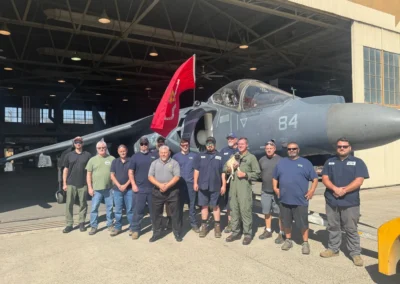 Group posing in front of military aircraft.
