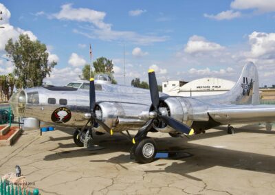 Silver vintage aircraft displayed outdoors on tarmac.